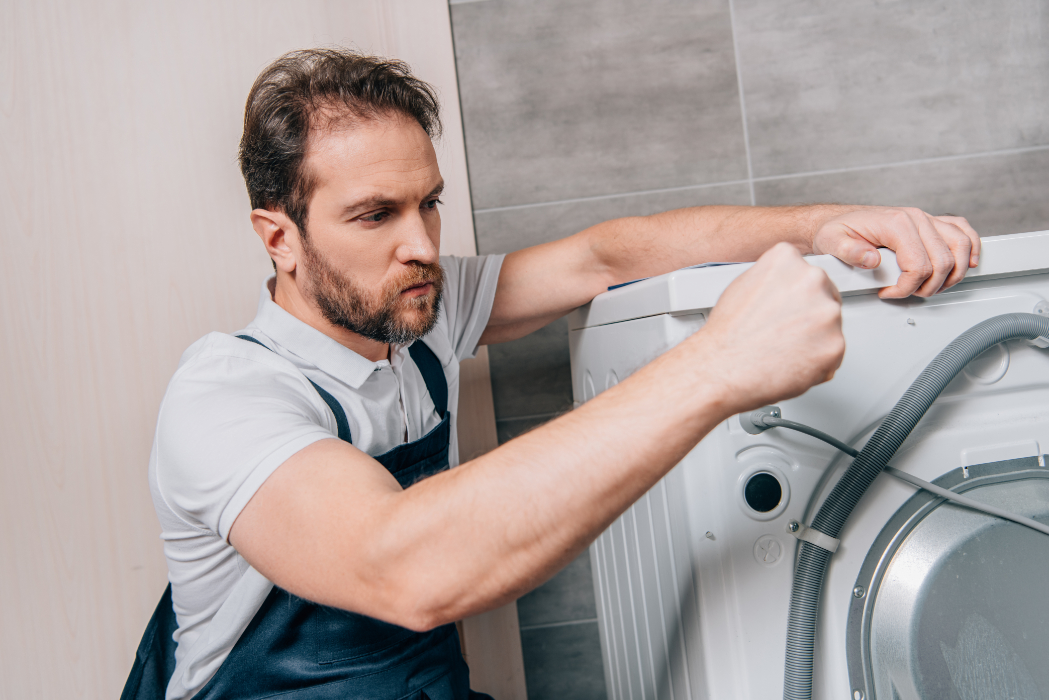confident male handyman repairing washing machine in bathroom